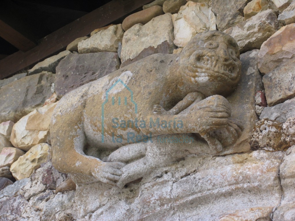 Detalle de la primitiva portada de acceso a las huertas del monasterio. Bestia con una figura humana entre las garras