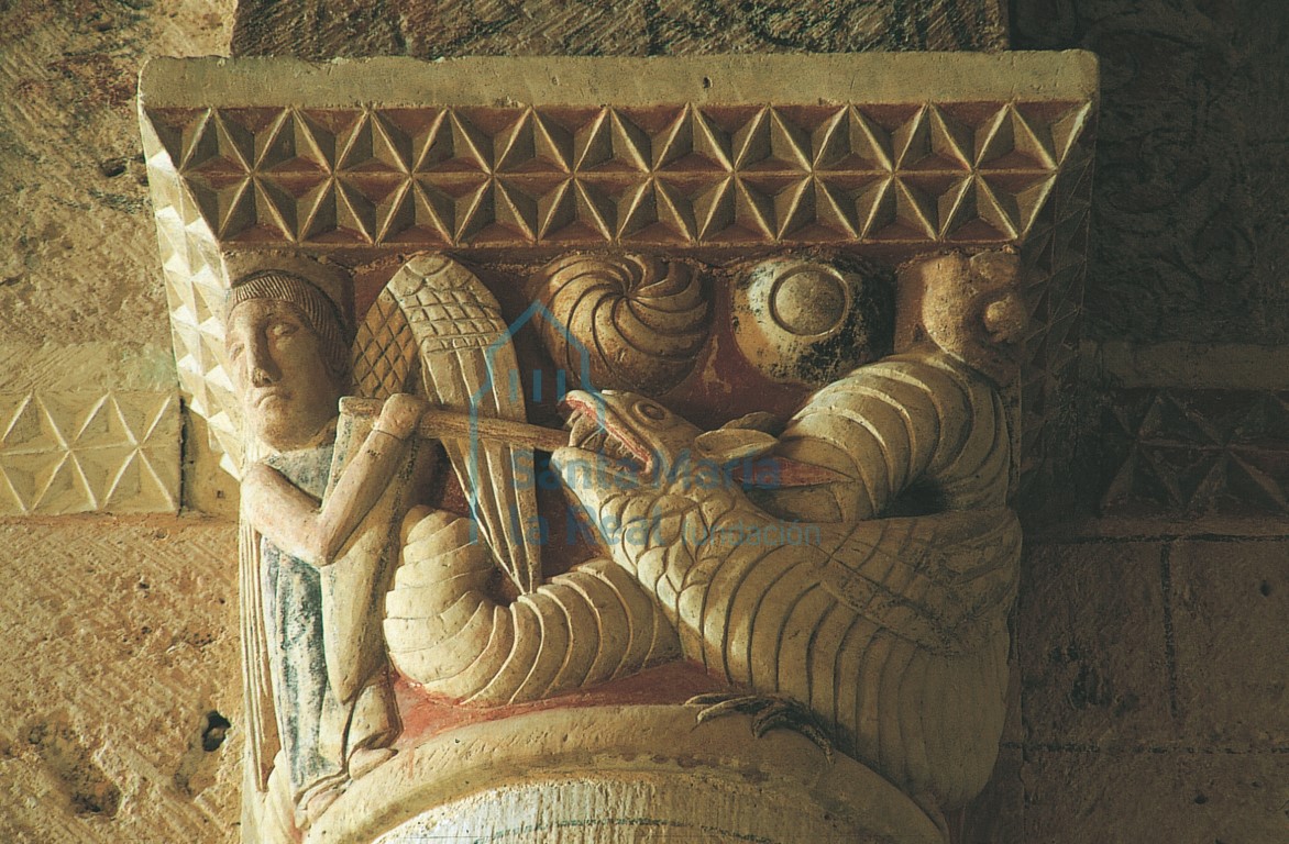 Capitel norte del arco triunfal. San Miguel, vestido con túnica y armado con escudo de cometa, alanceando al dragón.