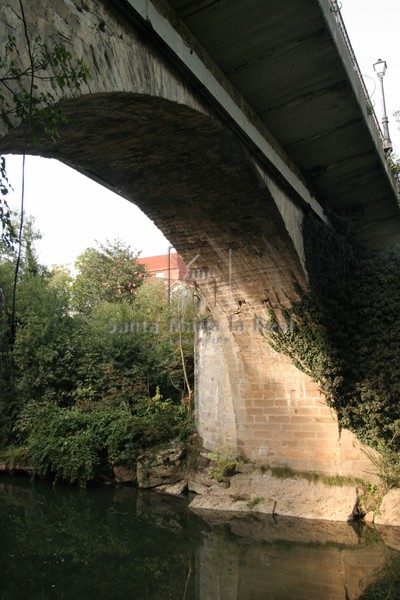 A la derecha, casi oculto por el arco del puente, se percibe parte del ábside románico