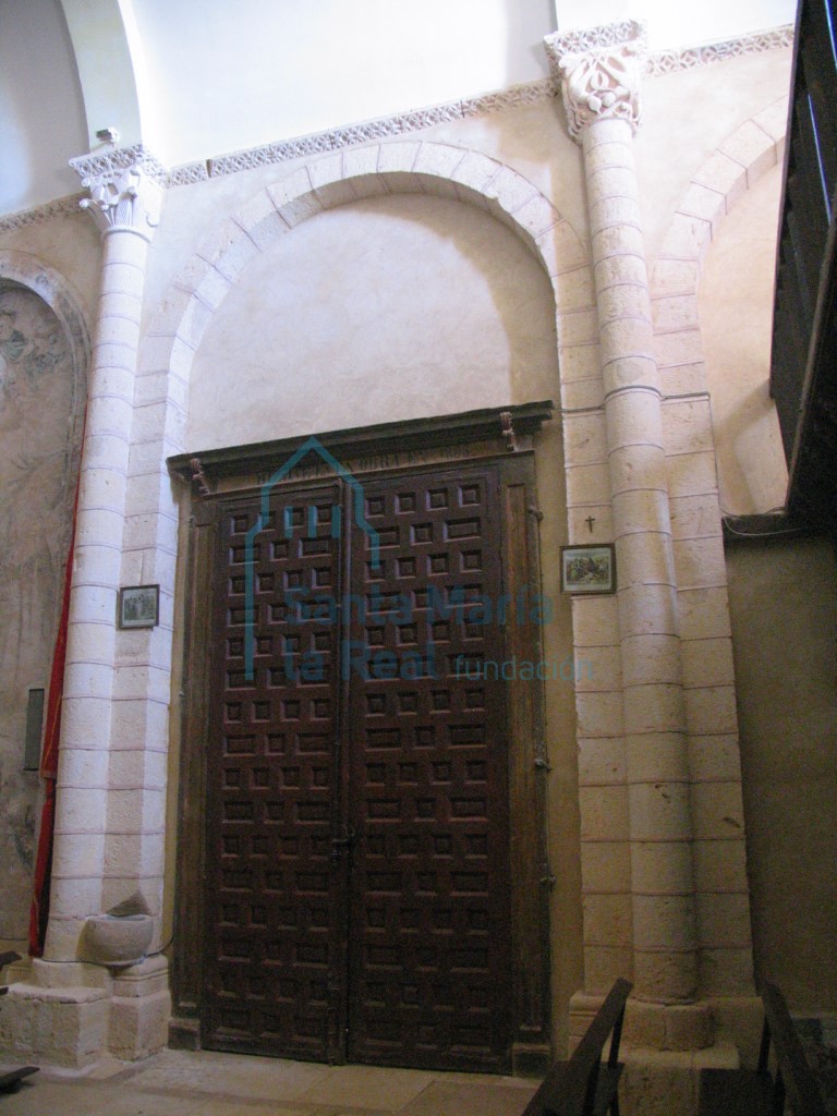Vista de un arco formero de medio punto dentro del cual se enmarca una puerta de entrada