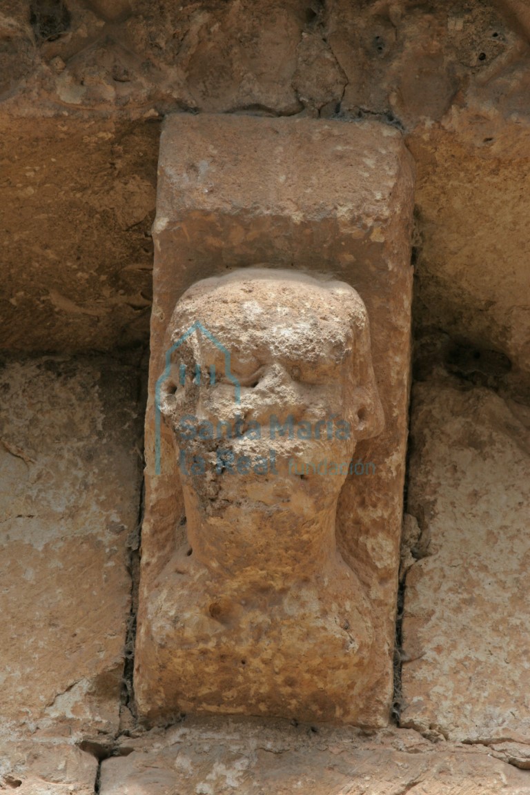 Canecillo en la cornisa de la galería porticada que representa un busto calvo y en posición frontal