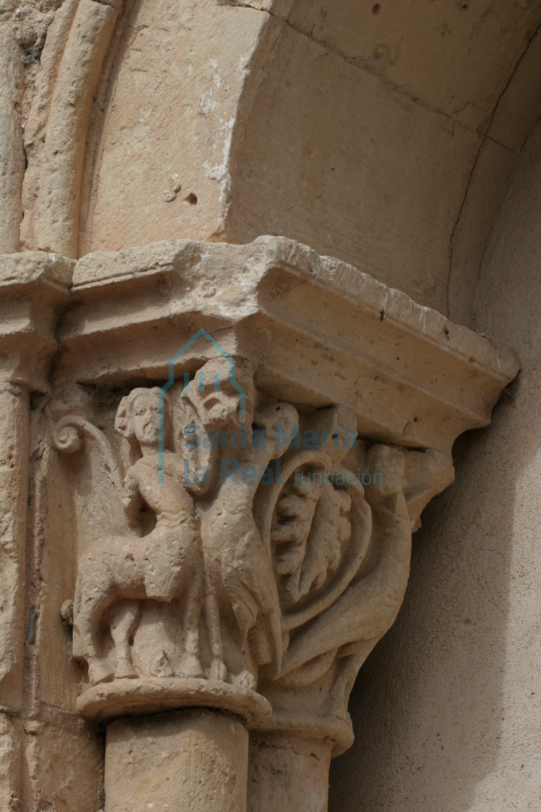 Capitel de la galería porticada figurada con ornamento en los ángulos de sendos centauros-sagitario de cabellera rematada en brotes vegetales que tensan sus arcos hacia estilizadas arpías de largo cuello vuelto