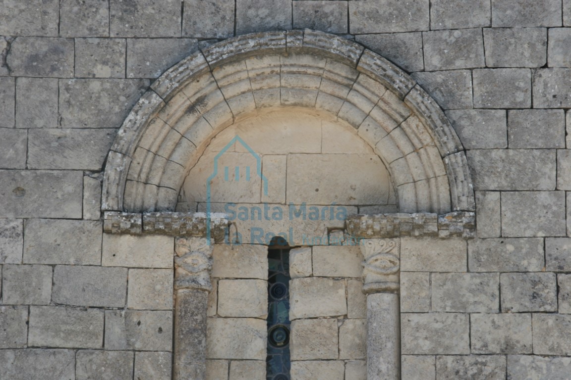Detalle del arco de medio punto moldurado con haz de triple bocel rodeado por chambrana abilletada de la ventana saetera del hastial occidental