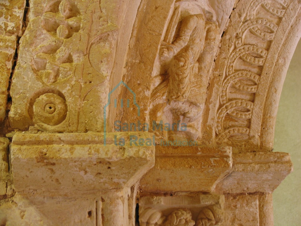 Detalle de la portada, en el que se puede ver la sencilla decoración de bezantes con tetrapétalas inscritas en círculos, tallados a bisel en el salmer de la izquierda