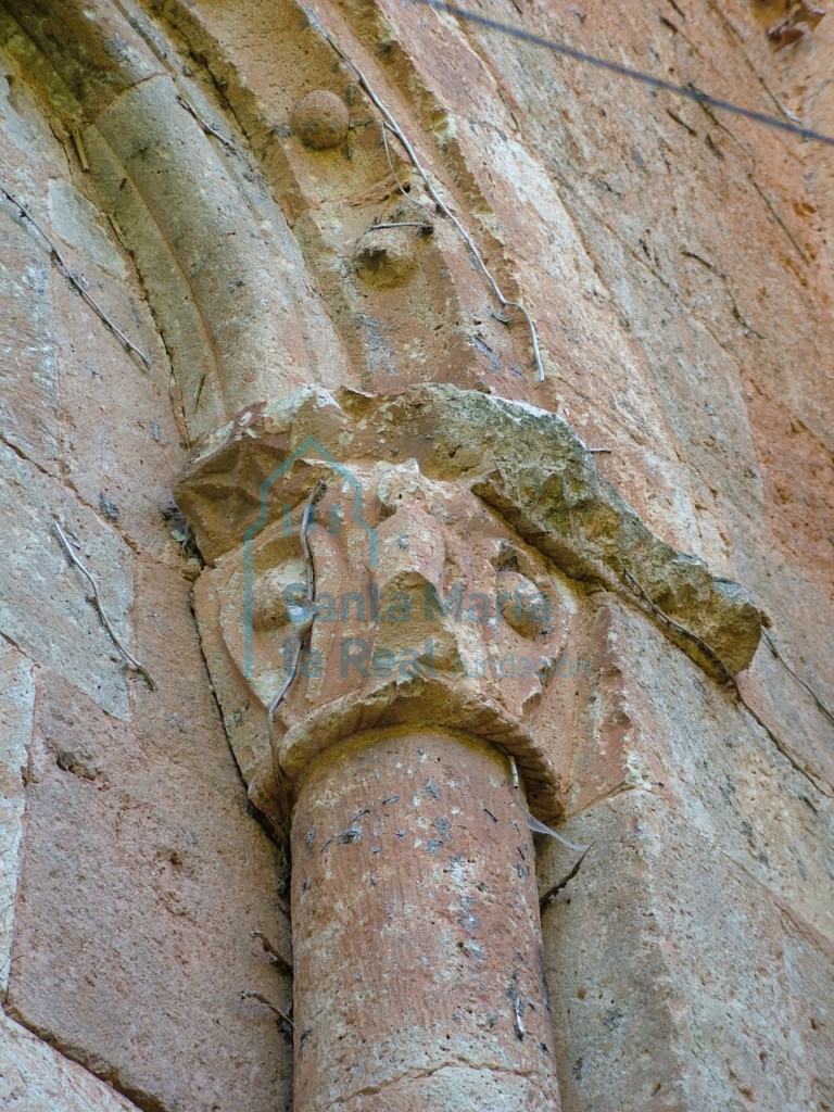 Detalle de la aspillera del ábside, en el que se observan la decoración con bolas, capitel ornamentado por una hoja muy esquemática en cuyo centro hay una bola