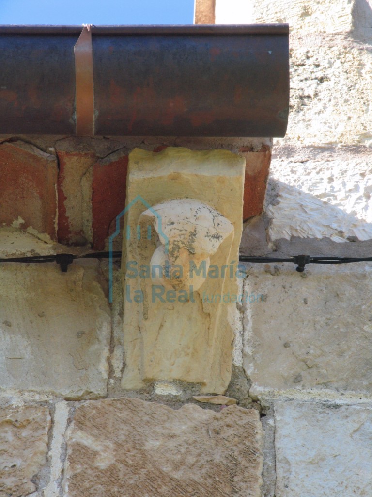 Canecillo con cabeza humana sobre la puerta de acceso en la fachada meridional