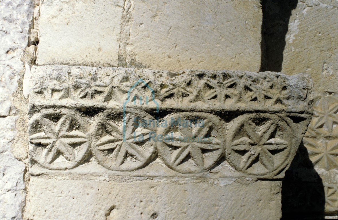 Imposta de perfil achaflanado ornada con series de circunferencias secantes conteniendo hojas hexapétalas en el lado izquierdo de la portada meridional