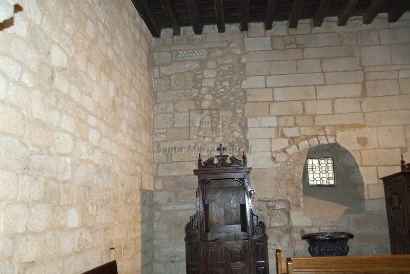 Interior del muro oeste con restos de una  línea de imposta románica en la parte superior junto a una puerta de arco de medio punto tapiada