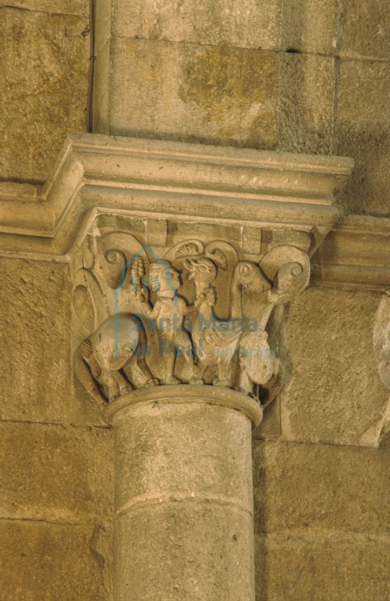 Capitel del pilar meridional del tramo oeste. Dos leones  en los laterales de la cesta y un personaje con una maza con puntas en su diestra y sujetando por el cuello a una extraña gallinácea
