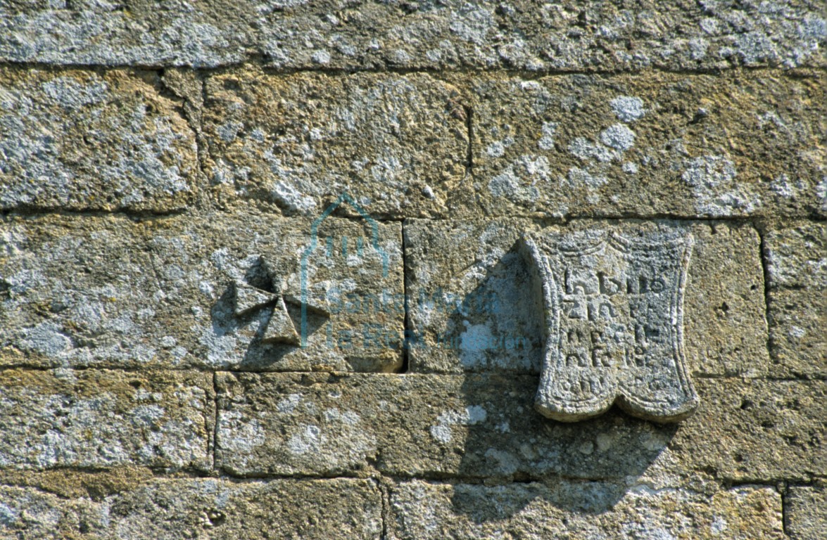 Detalle de una cruz de malta y una inscripción sobre la ventana del muro meridional de la cabecera